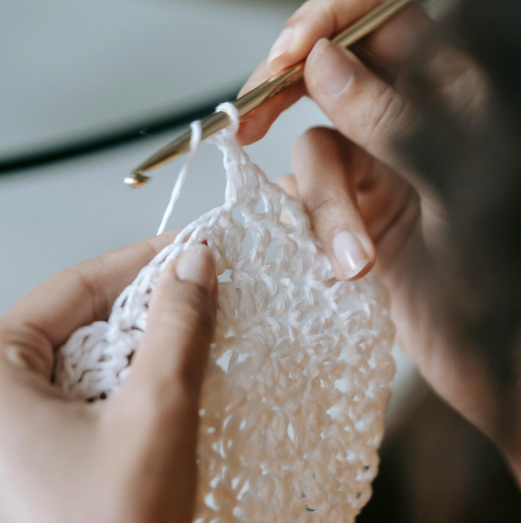 Detailed shot of hands skillfully knitting with a crochet hook and white yarn.